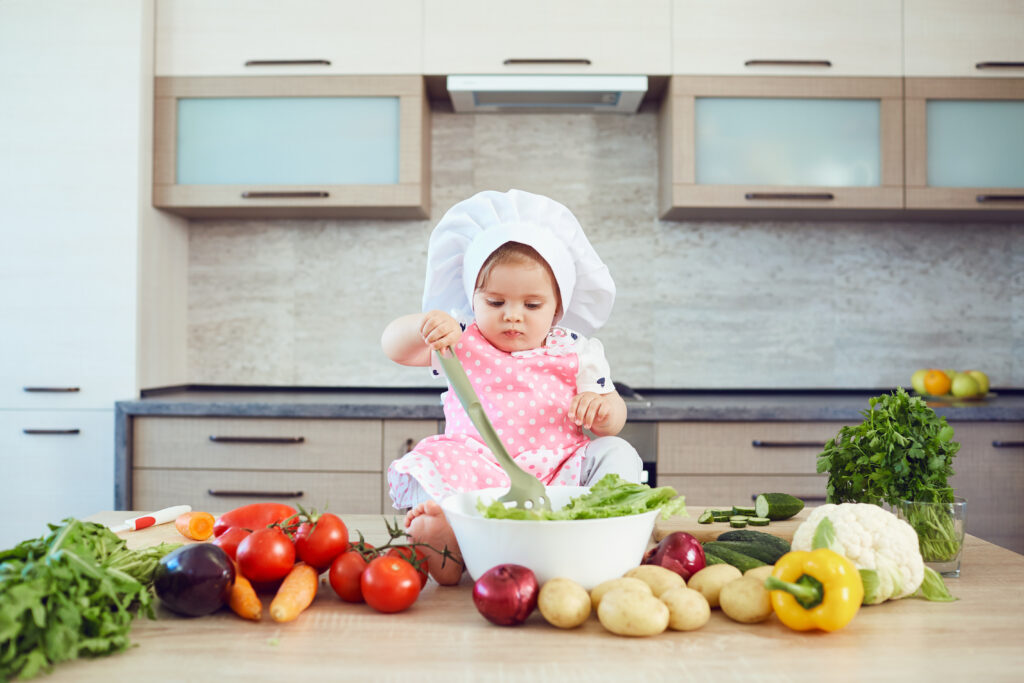 Dítě v kuchyni míchá čerstvou zeleninu bohatou na vitaminy podporující zdraví a plodnost.